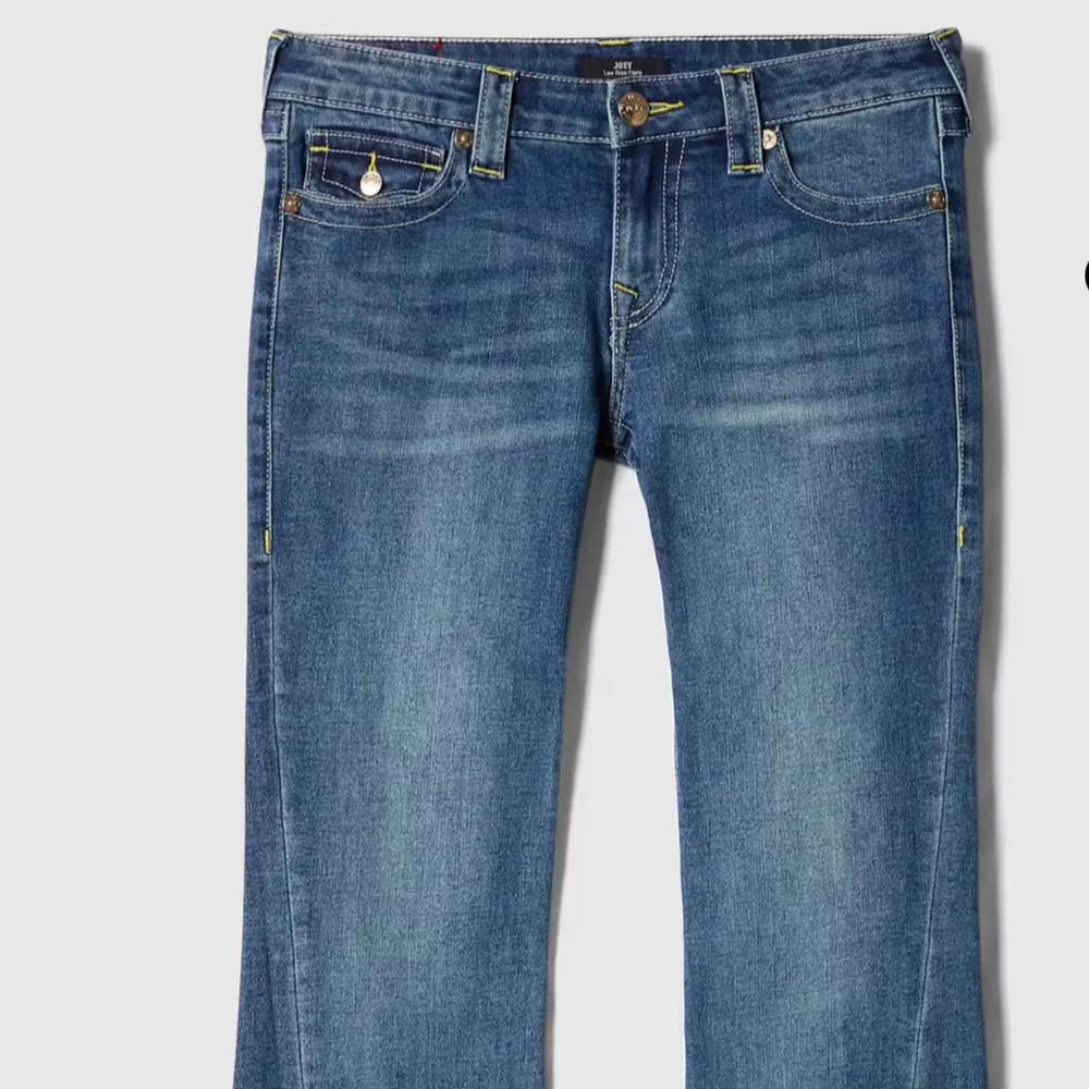 Säljer ett par klassiska blå jeans från True Religion med bootcut-passform. Jeansen har dekorativa sömmar och fickor med lock bak samt gylf med dragkedja och knapp. Perfekta för dig som gillar en tidlös jeansstil.. Farkut & Housut.