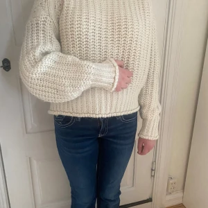 Vit stickad tröja med grov struktur - Säljer en chunky vit stickad tröja med breda ribbade muddar och avslappnad passform. Tröjan har långa ärmar och är perfekt för kyligare dagar. Enkel att matcha med jeans eller kjol för en stilren look.