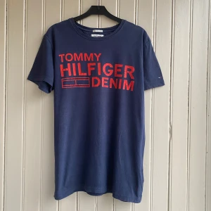 Tommy Hilfiger T-shirt  - En fin Tommy Hilfiger t-shirt med lite skadat tryck.   Måtten är cirka 45 i axelbredd och 70 i längd.  Tveka inte på att skriva om du har några frågor!💬 