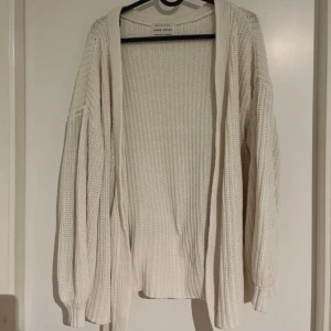 Vit stickad kofta från Sabo Skirt - Säljer en krämvit virkad kofta från Sabo Skirt i storlek XS. Koftan har lång ärm, öppen framtill och är gjord i ett mjukt, grovstickat material. Perfekt att slänga över en topp för en avslappnad look. Snöret tillkommer inte då jag inte har det! 