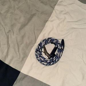 Flätat blått och vitt bälte med silverfärgat spänne - Säljer ett snyggt flätat bälte i blått, vitt och grått med ett silverfärgat spänne. Bältet har detaljer i mörkblått skinn vid spännet och änden. Perfekt accessoar för att lyfta din outfit.