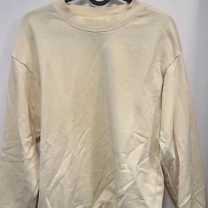 Beige sweatshirt från Monki - Säljer en enkel och stilren beige sweatshirt från Monki. Tröjan har rund halsringning och långa ärmar. Perfekt för en avslappnad och clean look. Passar dig som gillar basic och neutrala färger.