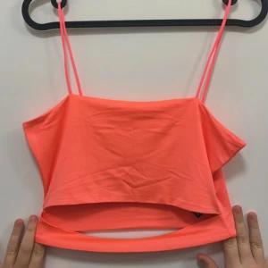 Neonrosa croppad linnetopp - Säljer en neonrosa croppad linnetopp med tunna axelband. Toppen har en enkel och stilren design med en snygg urklippning, perfekt för varma dagar eller som ett statement-plagg i garderoben.