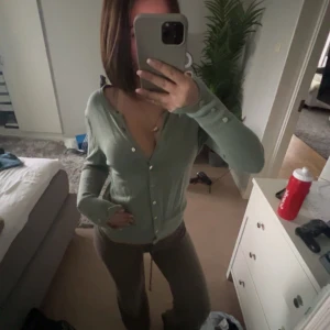 Ljusgrön kofta med pärlknappar - Säljer en ljusgrön kofta med pärlknappar och v-ringning. Koftan har långa ärmar och är i ett mjukt, tunt material som passar perfekt till lager-på-lager. Enkel och stilren design som funkar till mycket.