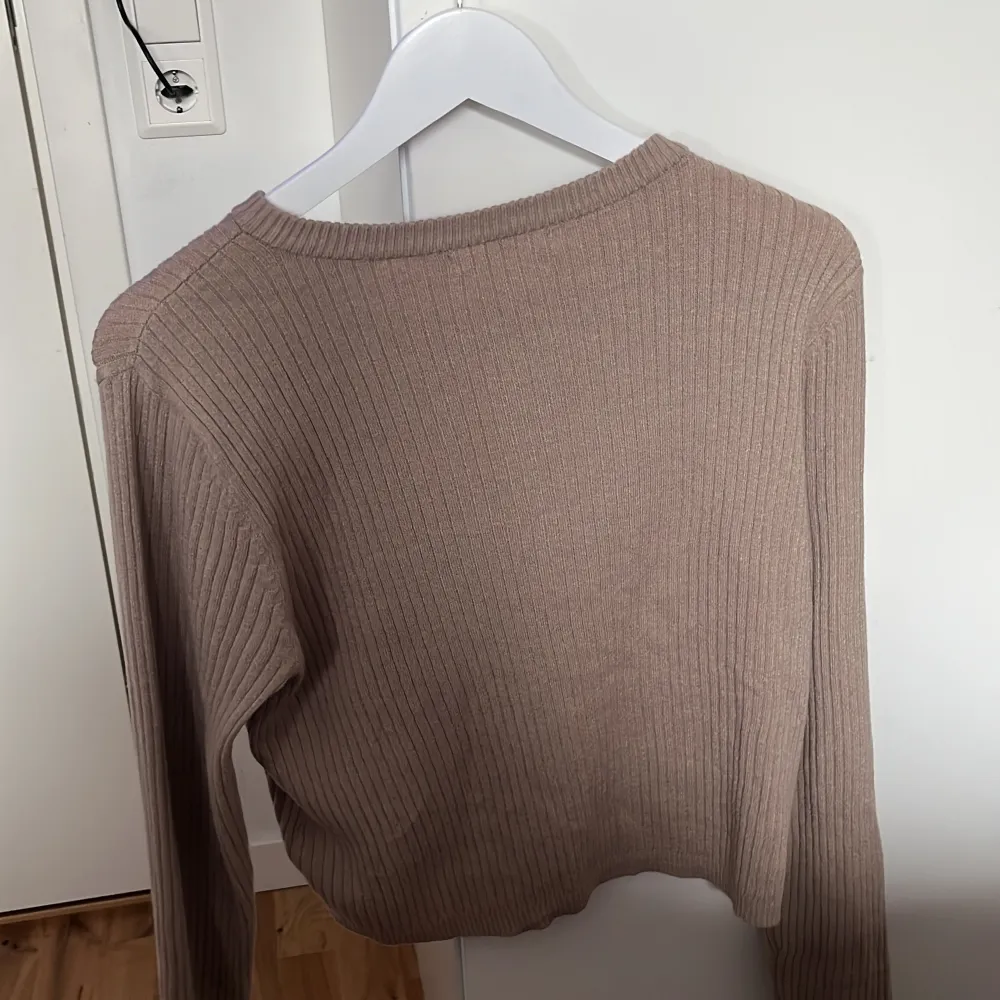 Säljer en beige ribbad kofta från 157 i storlek M. Koftan har långa ärmar, rund halsringning och knappar framtill. Perfekt att slänga över en topp för en enkel och stilren look.. Neuletakit & Villapaidat.