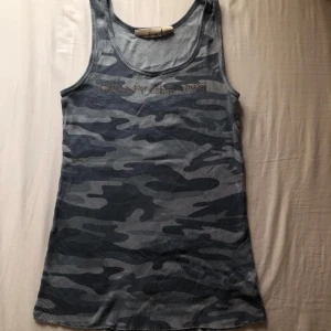 Blå camo linne  - Säljer en blå ribbad linne från DKNY JEANS med camouflagemönster och logga framtill. (skulle gissa at storleken är medium) 