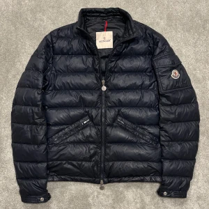 Moncler Agay - Tja! Säljer denna riktigt feta mörkblå (navy) Moncler Agay jackan! Jackan är i riktigt fint skick, har en liten lagning (bild 4), men den är väldigt diskret och märks inte av. Size 1, lite stor i storleken så passar perfekt på S. Självklart äkta! Skriv vid fler funderingar!