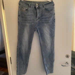 Blå jeans från Dazy, storlek XL - Snygga blå jeans från Dazy i storlek XL. Modellen har hög midja, raka ben och klassisk femficksdesign. Jeansen har ljus tvätt och stängs med två silverfärgade knappar. Perfekta till en avslappnad streetstyle-look.