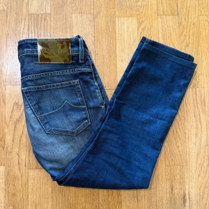 Jacob Cohën blå jeans med camo-detaljer - Snygga blå jeans från Jacob Cohën, modell 613, med coola camo-detaljer på fickor och insida. Jeansen har klassisk femficksdesign, kontrastsömmar och patch i pälsimitation bak. Tillverkade i mjukt denim med lätt tvättad look och raka ben.