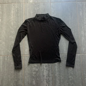 Svart polotröja från Zara - En svart polotröja från Zara i storlek M. Tröjan har lång ärm och en klassisk polokrage. Den är figurnära och tillverkad i ett mjukt, stretchigt material.
