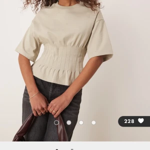 Beige korsett-topp med vida ärmar - Superfin beige korsett-topp med breda, korta ärmar och markerad midja. Toppen har en snygg, strukturerad look med sömmar som ger en figurnära passform och lätt volang nertill. Använt 2 gånger💞💞