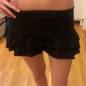 Miniskirt  - Supersöt kort svart kortkjol med volanger, inbyggda shorts och en fold down midja. Aldrig använd då den är för kort för mig! Inga defekter💗