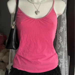 Rosa linnetopp med smala axelband - Snygg rosa linnetopp med smala axelband och lätt rynkning vid bysten. Den har en tight passform. Andvänd fåtal gånger, inga slitningar. Passar S-M