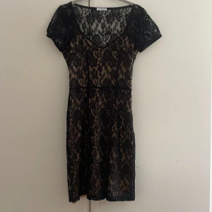 Spetsklänning från Ida Sjöstedt - Tight klänning i svart spets från Ida Sjöstedt! Klänningen har en beige underklänning och svart spets över och är i storlek 34 med en dragkedja i sidan! Köpte den secondhand och har inte fått användning för den då den inte riktigt är min stil!!