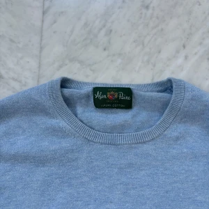 Ljusblå tröja från Alan Paine - Säljer en stilren ljusblå tröja från Alan Paine i mjuk kashmirmix. Tröjan har rund halsringning, ribbade muddar och klassisk passform. Perfekt för dig som gillar en enkel och clean look.