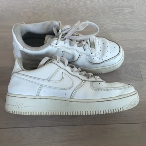 Vita Nike Air Force 1 sneakers - Kolla bilderna de är använda mycket. Klassiska vita Nike Air Force 1 sneakers i skinn med perforerad tå och snörning. Snygg och tidlös modell med låg profil och rund tå. Perfekta för dig som gillar streetstyle och vill ha en ikonisk sneaker i garderoben.