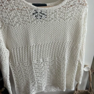 Vit stickad långärmad tröja - Superfin vit stickad tröja med lång ärm och snyggt virkat mönster över hela plagget. Perfekt för lager-på-lager och ger en chill men ändå stilren vibe. Passar lika bra till jeans som till kjol. Lätt och luftig känsla.