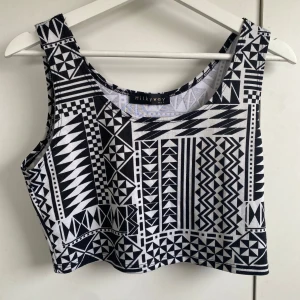 Svartvit mönstrad topp  - Snygg croppad topp från Milkyway med svartvitt geometriskt mönster. Toppen är ärmlös och har rund halsringning. Perfekt att styla med höga jeans eller kjol för en cool look. Står ingen storlek men skulle säga S/M. Köpt i USA.