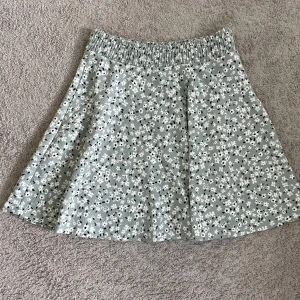 Blommig kjol  - Supersöt kjol från 157 i ljusgrönt med vita och svarta små blommor.