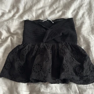 Svart broderad bandeau tubtopp ZARA - Supersöt svart bandeau tubtopp med smockad överdel och volangig nederdel i broderad bomull. Toppen har ett twistat parti framtill och fina blommiga broderier. Perfekt till sommaren och lätt att matcha med jeans eller kjol. Tyvärr för liten men verkligen så fin😻😻