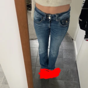 Blå bootcut jeans med dubbla knappar - Snygga blå jeans med bootcut-modell och dubbla knappar i midjan. Jeansen har inga tydliga tecken på användning och är inte slitna vid fötterna som de ofta kan vara. De är bara att skriva vid frågor💗