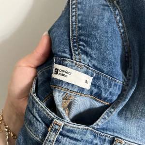 Blå denim byxdress från g perfect jeans - Snygg blå denim byxdress från g perfect jeans i storlek 36. Modellen har raka ben, breda axelband och dragkedja framtill. Klassisk jeanslook med fickor och bälteshällor, perfekt för en chill och trendig stil.