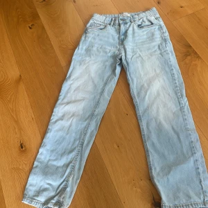 Ljusblå jeans från Lindex, strl 158 - Säljer ett par ljusblå jeans från Lindex i rak modell. Klassisk femficksdesign, normal passform och snyggt slitna detaljer vid benslutet. Perfekta för dig som gillar en avslappnad och enkel stil.
