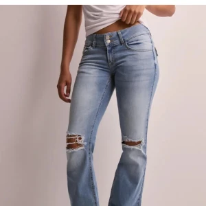 Ljusblå bootcut jeans från Nelly - Snygga ljusblå jeans från Nelly med bootcut passform och slitna hål över knäna. Jeansen har klassiska fem fickor, dubbla knappar i midjan och råa kanter vid bensluten. Bakfickorna har lock och knappdetalj. Den är upplagda några cm och passar mig som är 1,55 lång perfekt 😍 därav priset, som går att diskutera 