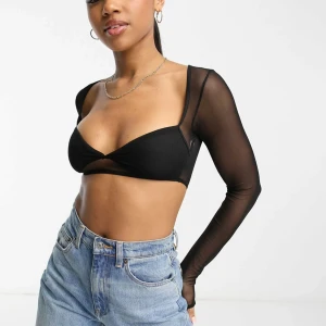 Svart mesh bolerotopp med långa ärmar - Säljer en svart, transparent bolerotopp i mesh med långärmad design och croppad passform. Perfekt att styla över linnen eller toppar för en edgy look. Tunn och lätt, med figurnära siluett och enkel rund halsringning.