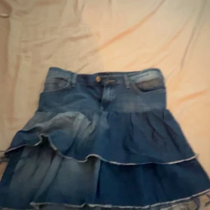 Volangkjol - Supersnygg blå jeanskjol från Lee med flera volanger och klassiska fickor fram. Knappt andvänd 