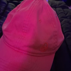 Orange keps från Sail Racing - Snygg rosa keps från Sail Racing i 100% bomull. Klassisk modell med böjd skärm och broderad logga framtill. Perfekt accessoar för en sportig och avslappnad look. Justerbar baktill för bästa passform.