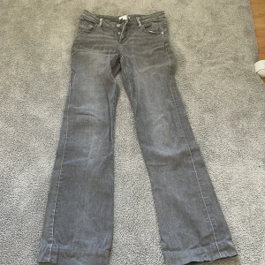 Grå bootcut jeans Gina Tricot 158 - Snygga grå jeans från Gina Tricot i storlek 158. Modellen har bootcut-ben och klassisk femficksdesign. Jeansen är tillverkade i mjukt denimtyg och har en cool, lite tvättad look. Perfekta för dig som gillar en avslappnad men trendig stil.