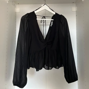 Söt svart volangtop med lite större ärmar - Söt svart volangtop med lite större ärmar. Passar S och M. Den har tyvärr rivits upp litegrann i v-ringningen men går att sy ihop superlätt. Aldrig använd ute men testat på och har då råkat varit lite för snabb i mina rörelser..