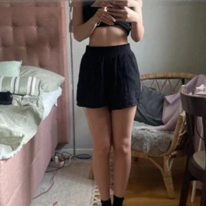 Svarta höga shorts i linne - Säljer ett par svarta höga shorts i luftig 100% viskos. De har elastisk midja och sidfickor, perfekt för varma dagar. Modellen är loose och ger en avslappnad vibe. Passar dig som gillar enkel och stilren look.