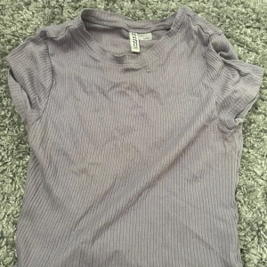 Ljuslila ribbad topp från H&M Divided - Superfin ljuslila ribbad topp från H&M Divided. Modellen är kortärmad med rund halsringning och har en slim passform som sitter snyggt. Perfekt att matcha med jeans eller kjol för en chill look.