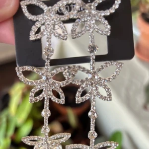 Glittriga silverörhängen med fjärilar - Långa statementörhängen i silverfärg med glittrande stenar formade som fjärilar. Örhängena har flera sammankopplade fjärilar och gnistrar rejält, perfekta för att sticka ut. Säljs på originalkortet.