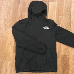 Svart vindjacka från The North Face - Svart vindjacka från The North Face. Jackan Perfekt för blåsiga dagar och enkel att matcha med allt. De finns inget fel på tröjan ingen sönder, fläck eller liknande