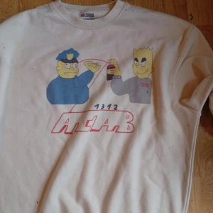 Vit sweatshirt Germes Gang / wizard bambino. Graffiti anti style M - Vit sweatshirt från Wizard Bambino i storlek L med stort tryck framtill av Simpsons-inspirerade figurer och texten ACAB. Tröjan har rund hals och långa ärmar, perfekt för dig som gillar streetwear och unika prints.