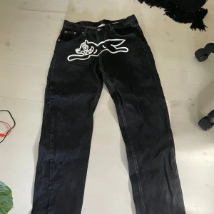 Svarta jeans med tryck från Billionaire Boys Club - Unika svarta jeans från Billionaire Boys Club med vit grafisk print framtill och astronauttryck på bakfickorna. Klassisk femficksmodell i rak passform, tillverkade i jeansmaterial. Perfekta för dig som vill sticka ut med coola detaljer.