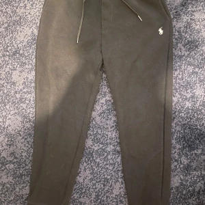 Svarta mjukisbyxor Polo Ralph Lauren - Svarta mjukisbyxor från Polo Ralph Lauren med dragsko i midjan och liten broderad logga på höften. Byxorna har en bakficka och är tillverkade i mjukt bomullsmaterial. Perfekta för chill dagar eller när du vill vara bekväm men ändå se snygg ut.