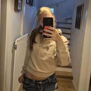 Beige hoodie  - Snygg beige hoodie med huva och snörning från NA-KD. För liten för mig, stl xxs. Använd en hel del men inga noppror eller liknande. Har en färgfläck på armen. (se bild 4) Går möjligtvis bort i ordentlig tvätt!
