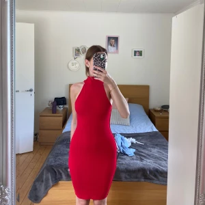 Röd ribbad ärmlös klänning - Säljer en tight, ärmlös röd klänning med hög krage och ribbad struktur. Klänningen är kort och har en figurnära passform som framhäver siluetten. Perfekt för dig som vill sticka ut med en enkel men snygg look.