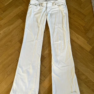 Vita bootcut jeans från  Rock & Republic - Snygga vita jeans från Rock & Republic i bootcut-modell. Byxorna har klassisk femficksdesign, silverfärgade nitar och glittriga detaljer på fickorna. Midjemått och ineerbenslängd på bild 4 och 5. Köpta på Plick för ett tag sedan, men jag säljer då de var alldeles förstora. Det är fläckar längst ner som säkert går bort i tvätten.( men då jeansen var förstora har jag aldrig använt eller tvättat de, så jag är inte säker)💕