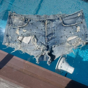 Jeansshorts med nitar - Snygga blå jeansshorts med slitna kanter och coola nitar framtill. Shortsen har låg midja. Perfekta för sommaren när du vill sticka ut med en bra vibe.💗