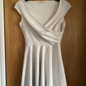 Vit omlottklänning.  - vit kortklänning från NLY One med omlott-detalj och v-ringning. Klänningen har korta ärmar och ett flowy kjolparti som ger en feminin siluett. Använd fåtal gånger. 