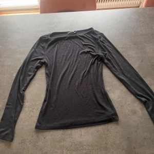 Svart långärmad topp från 157 - En svart, enkel och stilren långärmad topp från 157. Modellen är figurnära med rund halsringning och mjukt material som känns skönt mot huden. Perfekt att styla med jeans eller kjol för en clean look.