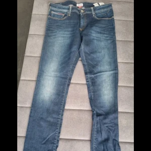 Hilfiger Denim blå slim jeans - Snygga blå jeans från Hilfiger Denim i modellen Scanton Slim. Jeansen har klassisk femficksdesign, snygga slitningar och kontrastsömmar. Passformen är slim och materialet är mjukt denim med en skön känsla. Perfekta för dig som gillar stilrena och moderna jeans.