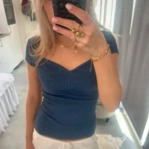 Mörkblå ribbad topp med v-ringning - Supersnygg mörkblå ribbad topp med v-ringad hals och korta ärmar. Sitter tight och har en smickrande passform som framhäver figuren. Perfekt att matcha med både jeans och kjol för en trendig look.🥰🥰