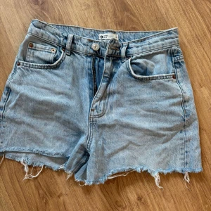 Ljusblå jeansshorts med fransig kant - Snygga ljusblå jeansshorts från Gina Tricot med fransig rå kant och klassisk femficksdesign. Perfekta för sommardagar och har en avslappnad loose fit. Stängs med knapp och dragkedja. Passar dig som gillar en chill och trendig stil.