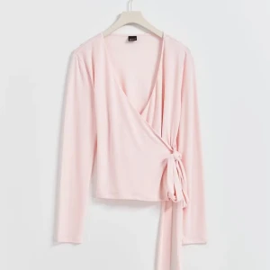 Ljusrosa Wrap tie top Gina tricot  - Super söt rosa omlott topp med knytning i sidan, storlek S. Bara använt några få gånger och är i mycket bra skick. Slutsåld på hemsidan!